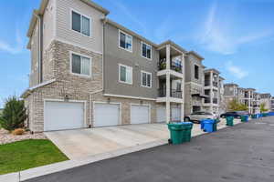 View of building exterior featuring a residential view, concrete driveway, and a garage
