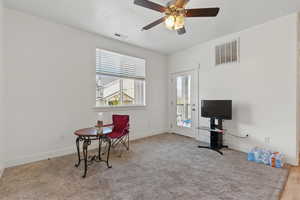 Living area featuring baseboards, visible vents, ceiling fan, and carpet floors