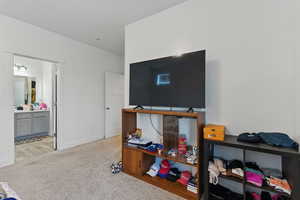 Bedroom featuring ensuite bath, light carpet, and baseboards