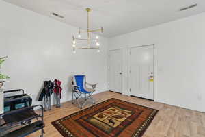 Entrance foyer with wood finished floors, visible vents, and a chandelier