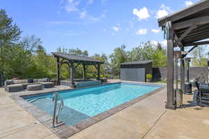 View of heated swimming pool with pump shed,  patio area, and covered hot tub