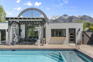 Back of house featuring brick siding, a mountain view, patio area, and an outdoor heated pool