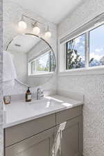 Bathroom with quart countertops, wallpaper and tile floors
