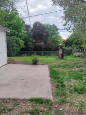 View of the back yard with fence and a patio area.