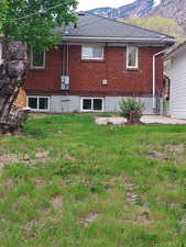 Rear view of property featuring a lawn, a mountain view.