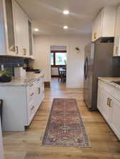 Kitchen with white cabinetry, granite countertops, and glass insert cabinets