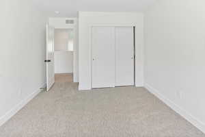 Unfurnished bedroom featuring baseboards, a closet, carpet flooring, and visible vents