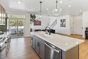 Kitchen with stainless steel dishwasher, a sink, stove, and light countertops