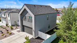 View of property exterior with driveway, a garage, fence, a shingled roof, and stucco siding