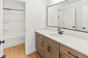 Full bath featuring vanity, baseboards, shower / bathing tub combination, and wood finished floors