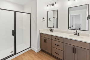 Full bath with a sink, a shower stall, and wood finished floors