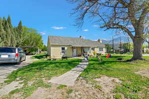 Bungalow-style house featuring a trampoline, a front yard, a mountain view, a chimney, and a detached carport