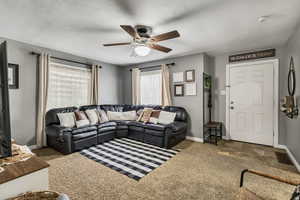 Carpeted living room featuring baseboards, a ceiling fan, and visible vents