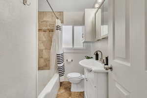 Bathroom with vanity, baseboards, shower / bath combo, and toilet