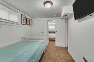 Bedroom with visible vents, a textured ceiling, baseboards, and light carpet