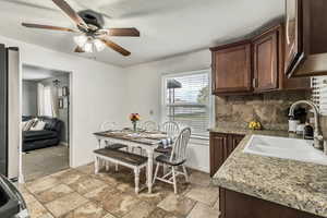 Kitchen with dark brown cabinetry, a sink, a ceiling fan, baseboards, and tasteful backsplash