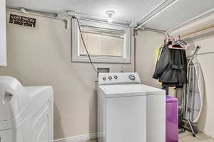 Clothes washing area with laundry area, light tile patterned flooring, and independent washer and dryer