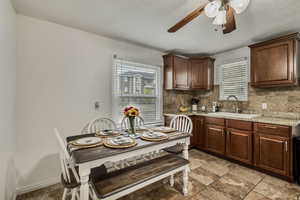 Eat-in Kitchen with a sink, tasteful backsplash, a ceiling fan, and stone finish flooring