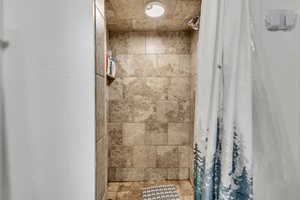 Bathroom featuring a tile shower and stone finish flooring