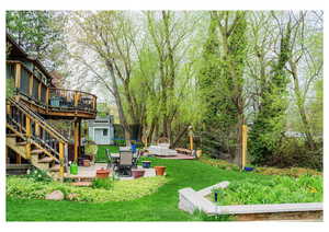 View of yard featuring a storage shed, a wooden deck, an outdoor structure, and a patio area