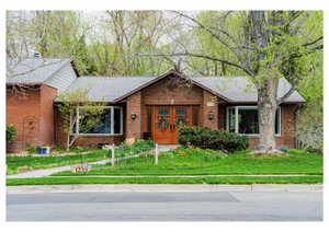 Ranch-style house with brick siding, roof with shingles, and a front yard