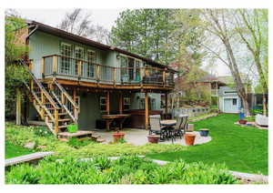 Rear view of property with a deck, a patio, a shed, a lawn, and a hot tub