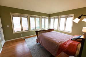 Bedroom with visible vents, baseboards, lofted ceiling, and wood finished floors