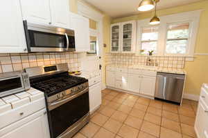 Kitchen featuring tile countertops, a sink, appliances with stainless steel finishes, and tasteful backsplash