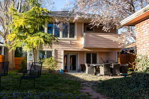 Back of property featuring a lawn, fence, and outdoor dining space