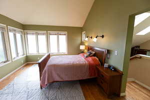 Bedroom with wood finished floors and vaulted ceiling with skylight