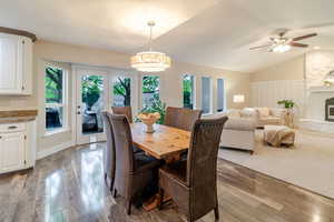 Dining space featuring hardwood / wood-style floors, ceiling fan, a fireplace, and lofted ceiling