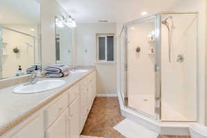 Bathroom with a stall shower, double vanity, and a sink