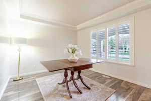 Dining area with crown molding, a tray ceiling, wood finished floors, and baseboards