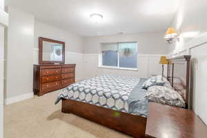 Carpeted bedroom with wainscoting and a decorative wall
