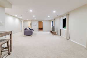 Living area featuring baseboards, recessed lighting, and light colored carpet