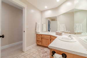 Bathroom with tile patterned floors, baseboards, double vanity, and a sink
