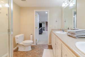Bathroom featuring a sink, double vanity, baseboards, toilet, and tile patterned flooring