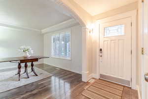 Entrance foyer featuring ornamental molding, arched walkways, a wealth of natural light, and dark wood-type flooring
