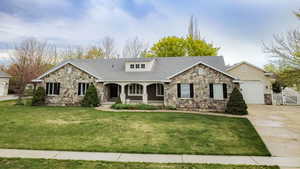 Craftsman-style home with a porch, a garage, driveway, stone siding, and a front lawn