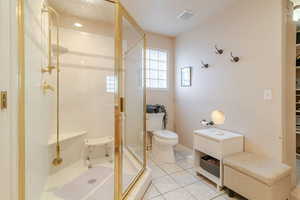 Bathroom featuring visible vents, a stall shower, toilet, and tile patterned flooring