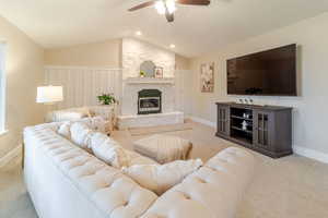 Carpeted living area with recessed lighting, ceiling fan, a fireplace, baseboards, and lofted ceiling