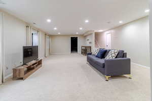 Living area with recessed lighting, stairs, and light colored carpet