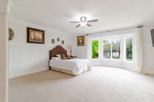 Bedroom with ornamental molding, carpet flooring, and a decorative wall