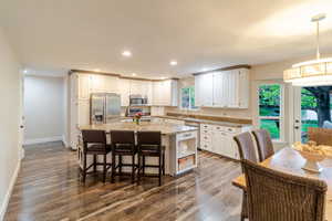 Kitchen with dark wood-style floors, white cabinets, stainless steel appliances, and a kitchen island