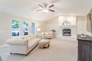 Living area with ceiling fan, vaulted ceiling, and a fireplace