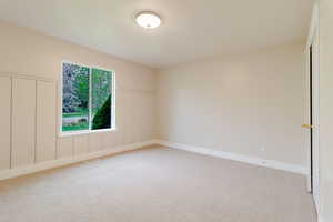 Spare room featuring visible vents, baseboards, wainscoting, and light carpet