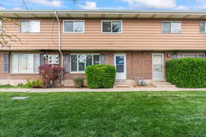 View of property featuring brick siding, entry steps, and a front lawn