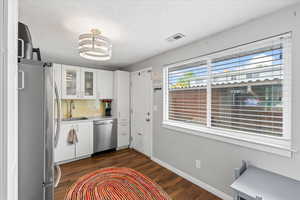Kitchen featuring white cabinets, stainless steel appliances, dark wood-style floors, and a sink