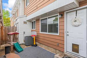 Doorway to property featuring central air condition unit and fence