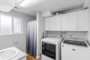 Washroom featuring independent washer and dryer, laundry area, a sink, wood finished floors, and visible vents
